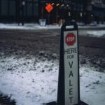 Snowy city street with a valet parking sign, perfect urban winter scene.