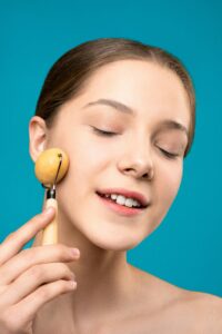 Woman enjoying a relaxing facial massage with a roller for youthful skin.