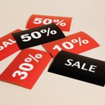 Red and black sale tags showing various discount percentages on a beige background.